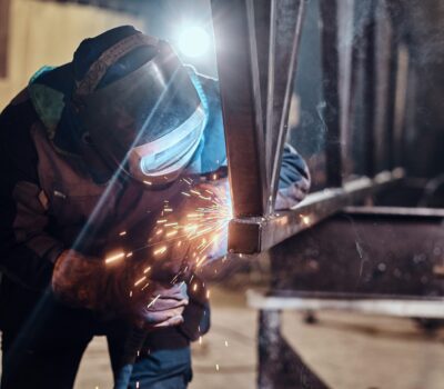 Man is working at metal factory, he is welding a piece of rail using special tools.